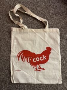Tote Bag featuring a red print of a rooster motif with the word "cock" on it
