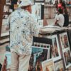 Man in Floral Print Shirt Standing in Front of Paintings